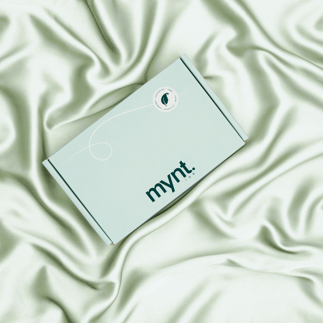 Mynt Lab mint green packaging box on sage green vegan silk bedding, showcasing soft folds and luxurious plant-based fabric