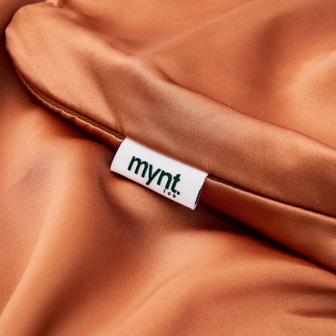 Close-up of terracotta vegan silk pillowcase with Mynt Lab label on plant-based fabric