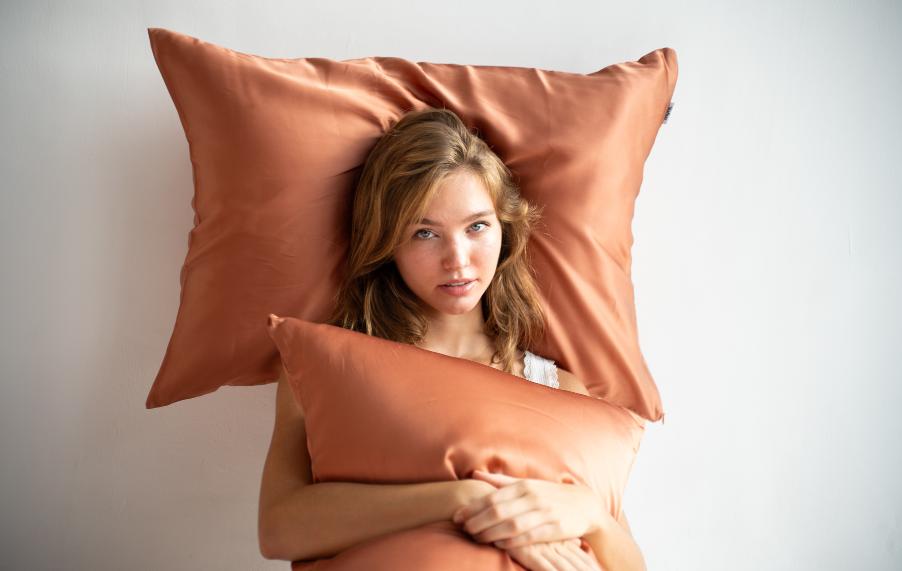 Woman with healthy skin and hair resting on terracotta MyntFusion™ cooling pillowcases