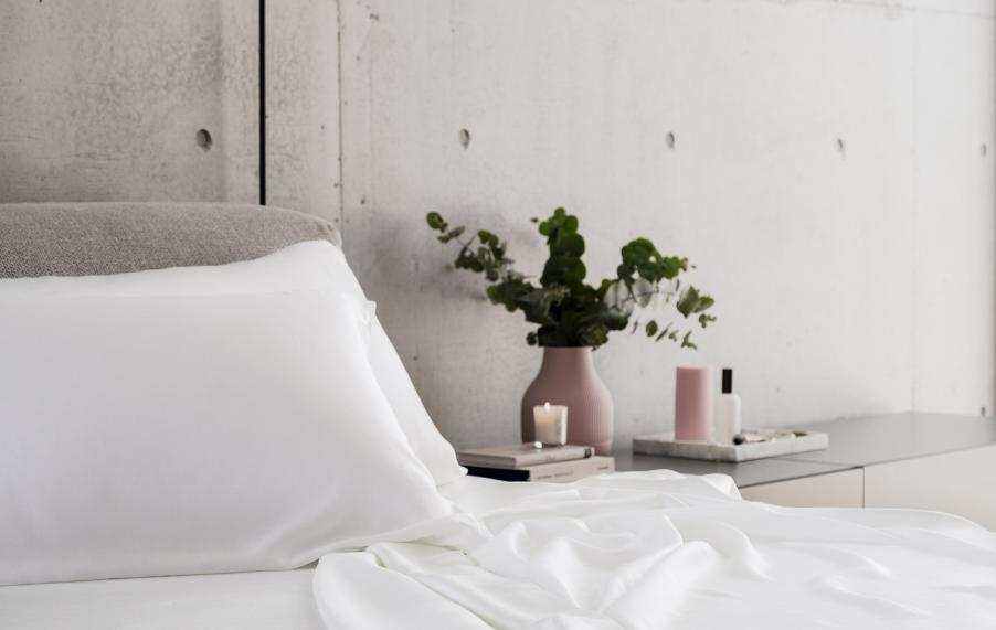 Wind-down routine bedroom with white cooling sheets and calming bedside candles