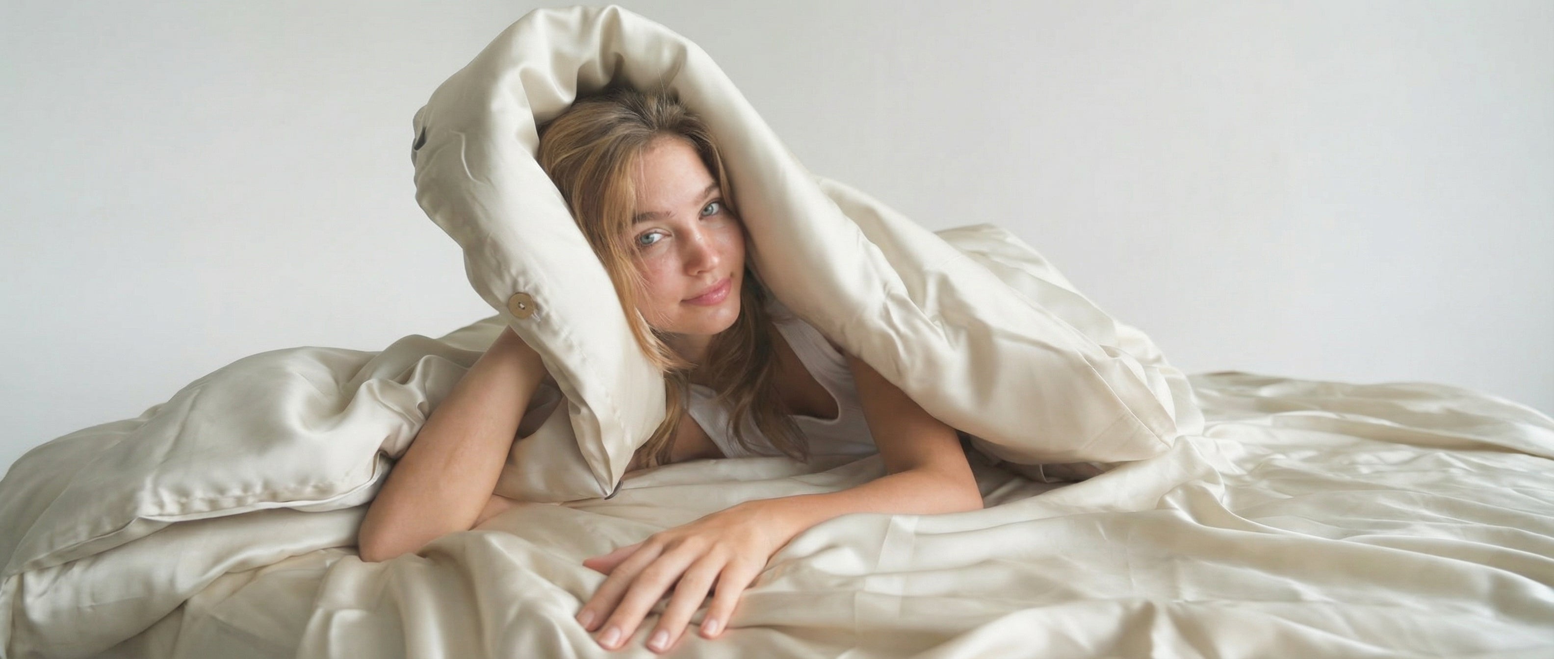 A neatly folded, plain white comforter or duvet on a light gray background.