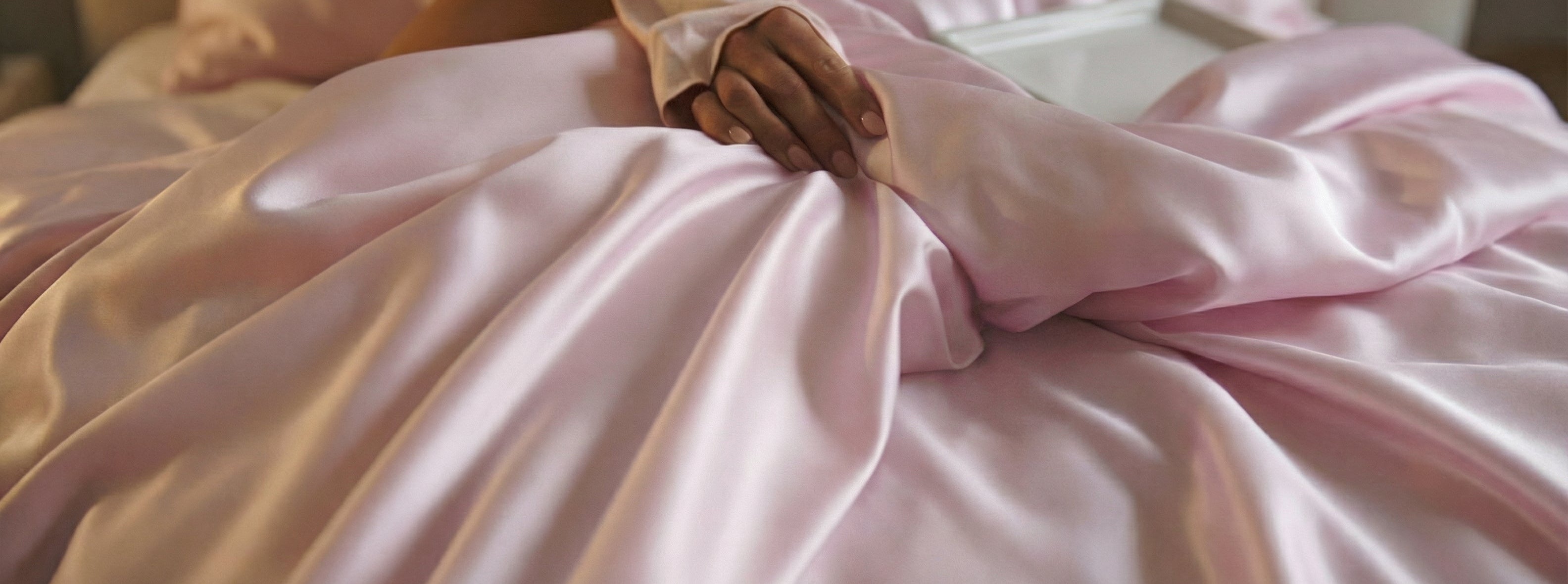 A woman in light pink sleepwear and a matching head wrap lies on a bed with pink sheets outdoors in a forest. Text reads: Gift Voucher and mynt.