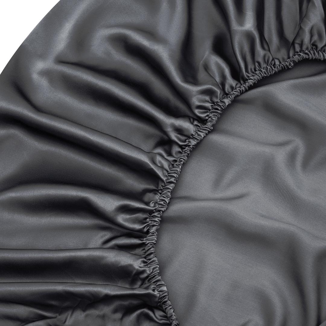 Close-up of the Fitted Sheet Set (3-Piece) in charcoal, featuring gathered elastic edges, silky soft and shiny fabric, plus elegant ruffled corner details - ideal for anyone wanting smooth, luxurious sheets.