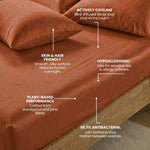 A terracotta bed sheet set on a wooden bed frame with text highlighting features: cooling mint-infused fibers, skin and hair friendly, plant-based performance, hypoallergenic, and 99.7% antibacterial.