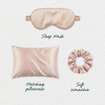 A blush pink satin Beauty Sleep Gift Set—sleep mask, pillowcase, and scrunchie—is displayed on a light textured background with handwritten labels for each: Sleep Mask, Matching Pillowcase, and Soft Scrunchie.