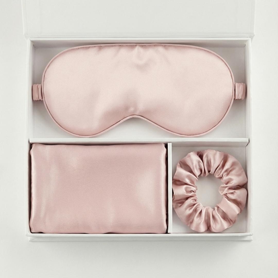 The Beauty Sleep Gift Set comes in a white box with a pink silky sleep mask, pillowcase, and scrunchie, each arranged in its own compartment for the ultimate beauty sleep experience.