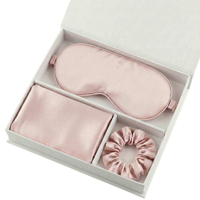 The Beauty Sleep Gift Set comes in a white box with essentials for a perfect night: a light pink silky sleep mask, folded pillowcase, and scrunchie, each neatly arranged in separate compartments.