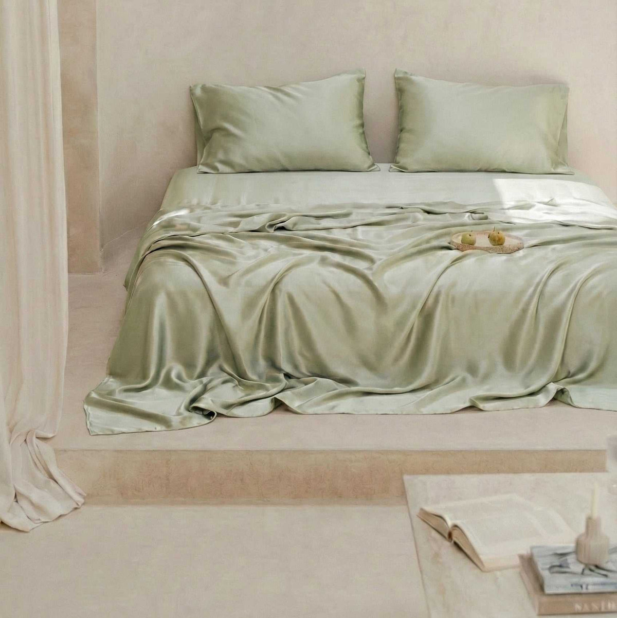 Bed with green bedding and pillows against a beige wall.