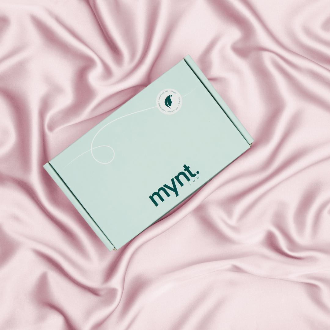 A mint green mynt lab box rests on pale pink, silky fabric -perfect for pairing with the Deep Sleep Bundle for ultimate relaxation.