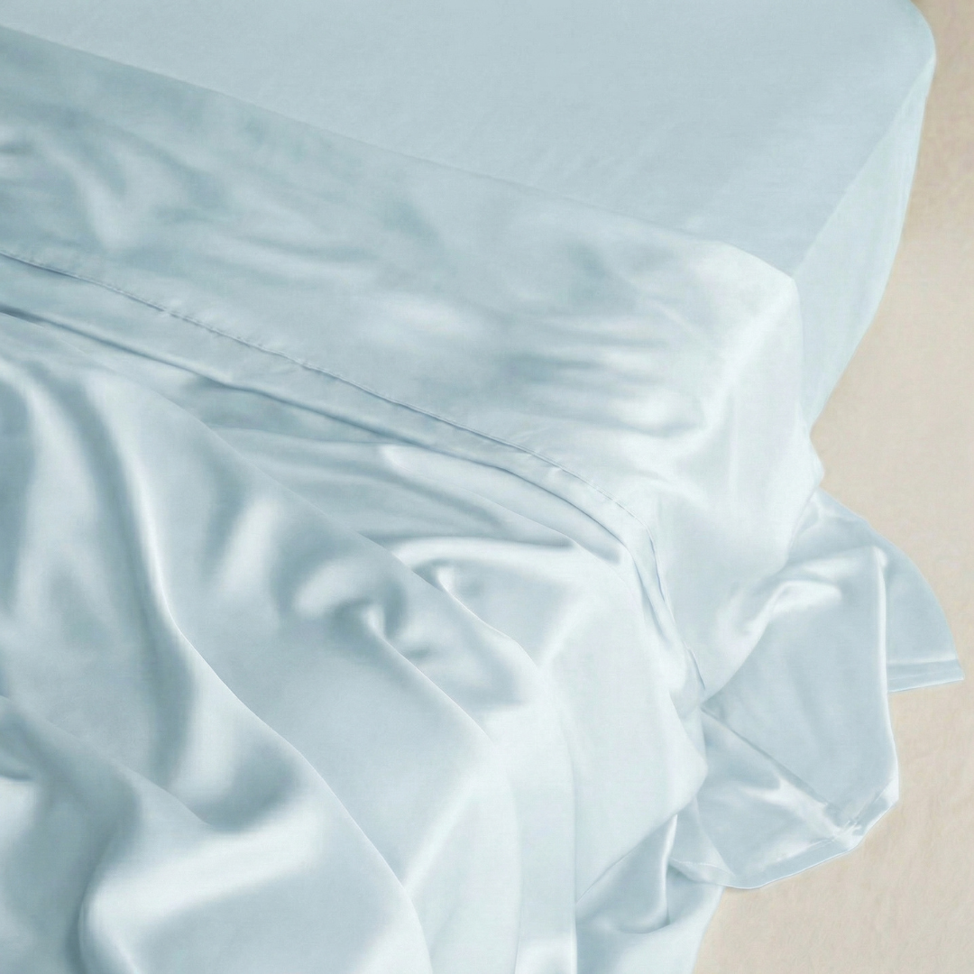 Powder Blue MyntFusion™ mint-infused flat sheet draped over a bed, showcasing its silky, cooling fabric.