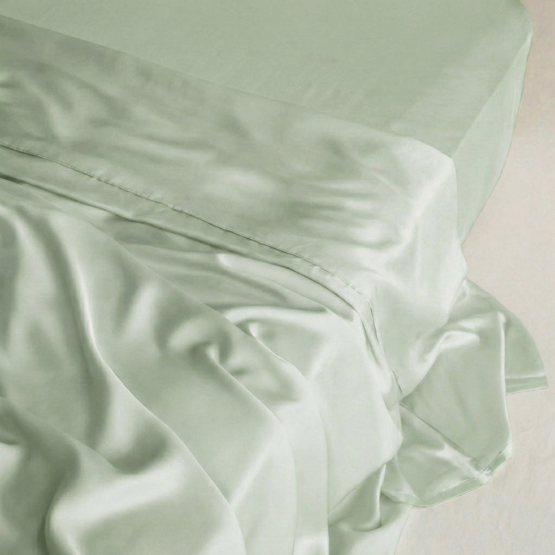 Sage Green MyntFusion™ flat sheet, smooth and silky, draped on a bed.