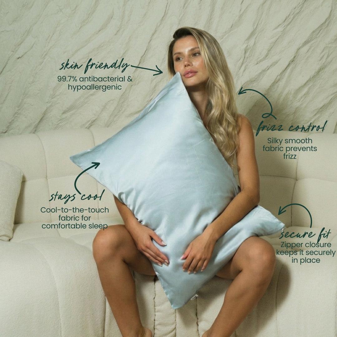 A woman sits on a cream sofa hugging a large, light blue MyntFusion™ Pillowcase by Mynt Lab, crafted from silky-smooth fabric. Text highlights its benefits: skin-friendly, reduces frizz, stays cool, and features a secure zipper closure.