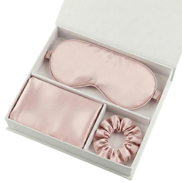 The Beauty Sleep Gift Set comes in a white box with essentials for a perfect night: a light pink silky sleep mask, folded pillowcase, and scrunchie, each neatly arranged in separate compartments.