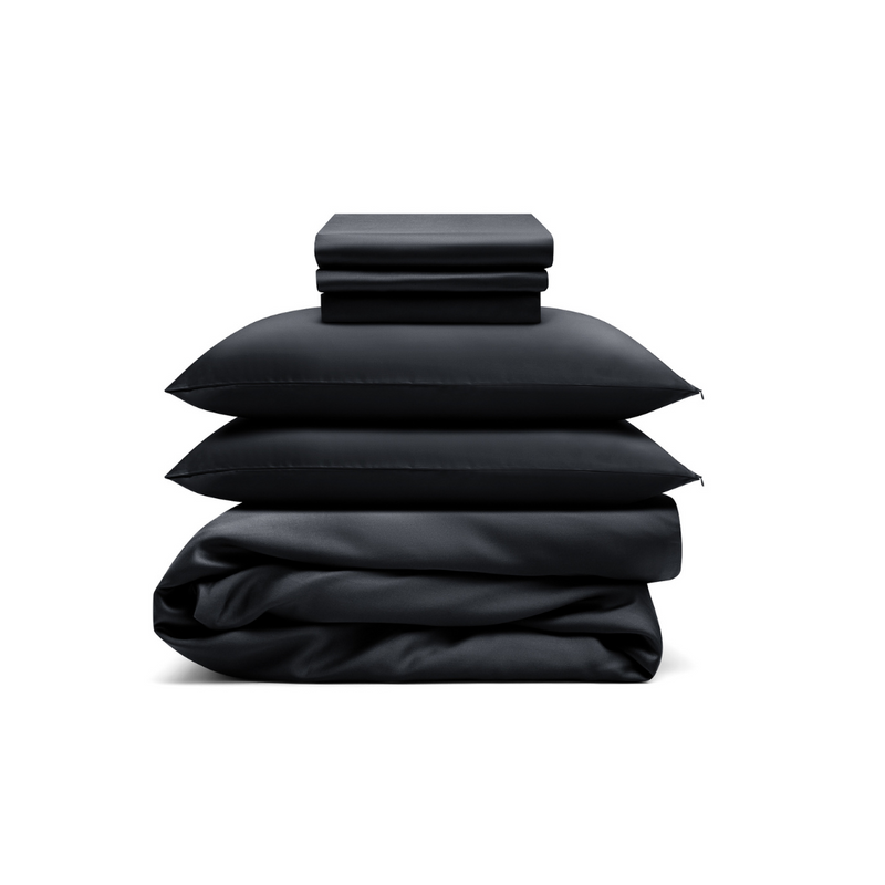 The Bedding Bundle, a customizable set in black, includes folded sheets, two pillows, and a comforter, all neatly stacked against a white background.