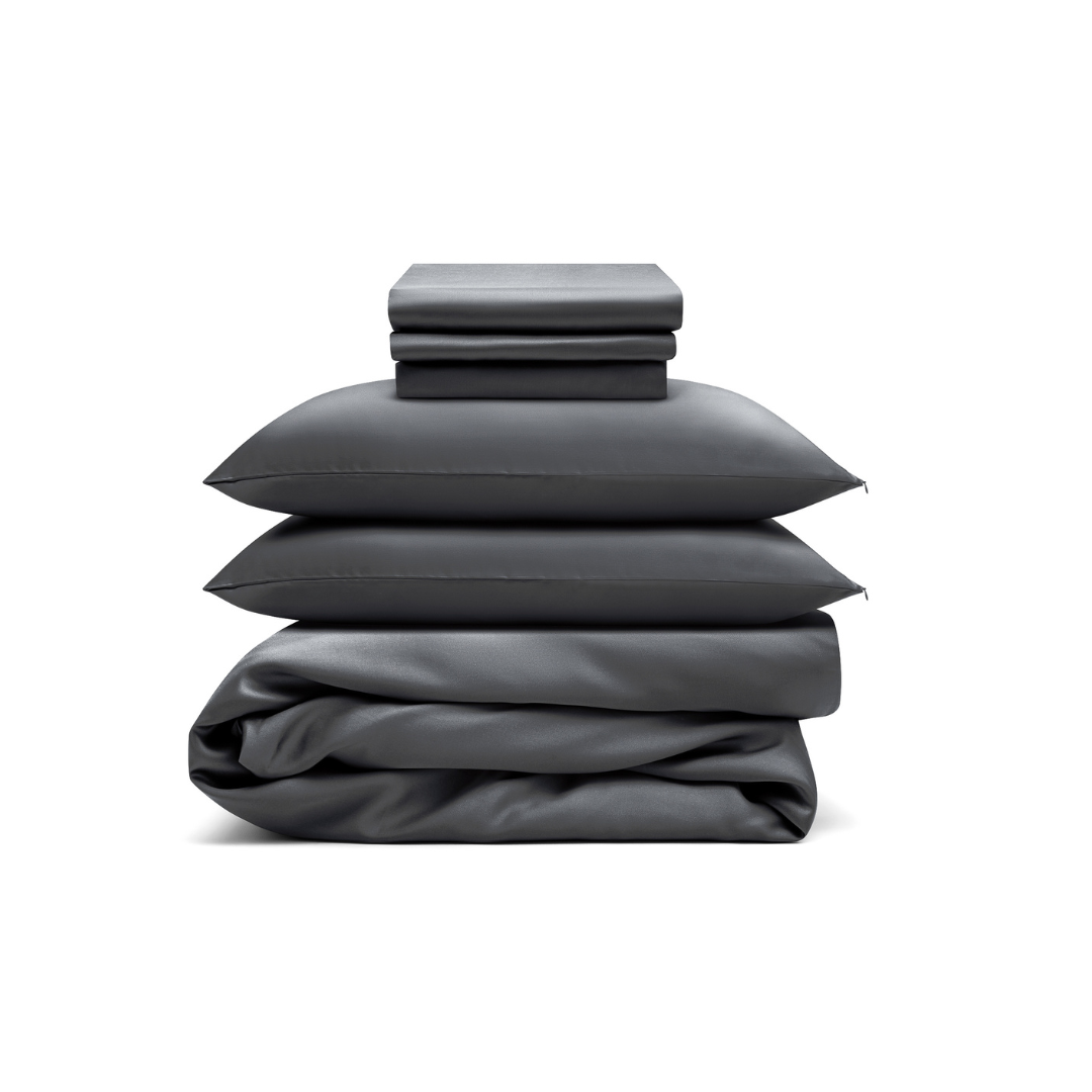 A Bedding Bundle in dark gray, featuring two pillowcases, a folded sheet, and a folded duvet cover, neatly stacked against a white background.