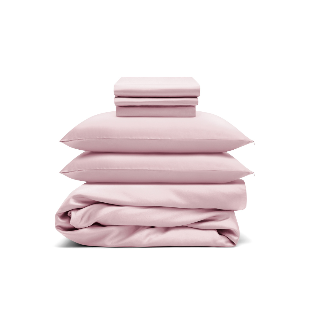 The Bedding Bundle features a neatly stacked set of light pink cooling bedding—two pillows, folded sheets, and a comforter—displayed against a white background.