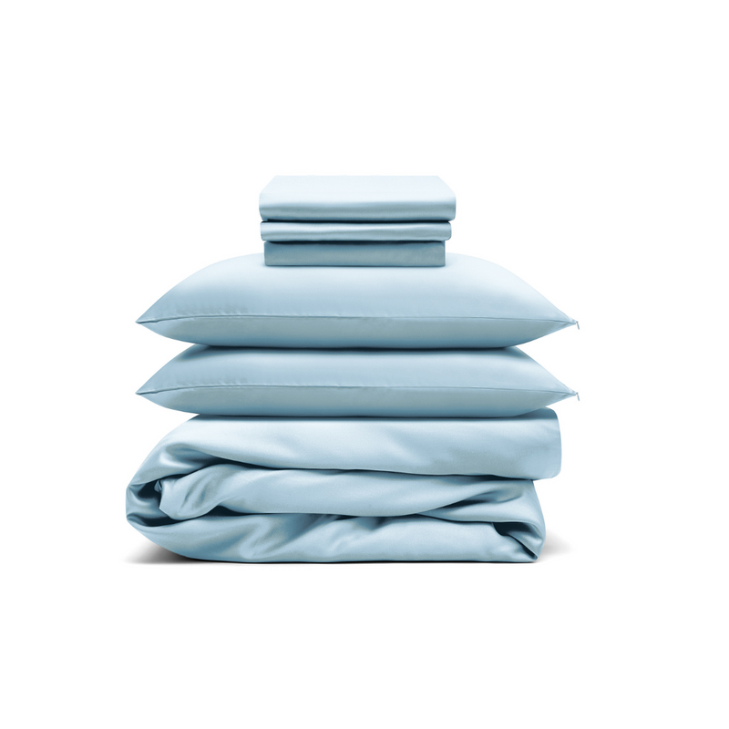 The Bedding Bundle, featuring light blue antibacterial sheets, pillowcases, and a comforter, is neatly stacked and folded against a white background.