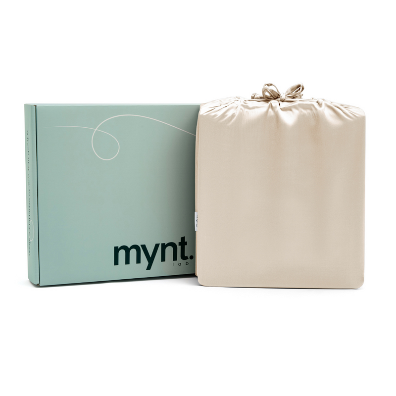 A pale green mynt lab box stands beside a sand silky drawstring bag against a white background - the perfect presentation for the Fitted Sheet Set (3-Piece).