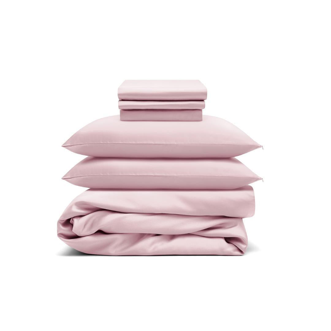 The Bedding Bundle features a neatly stacked set of light pink cooling bedding - two pillows, folded sheets, and a duvet cover - displayed against a white background.