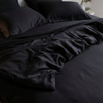 Black bedding set on a bed with dark pillows.