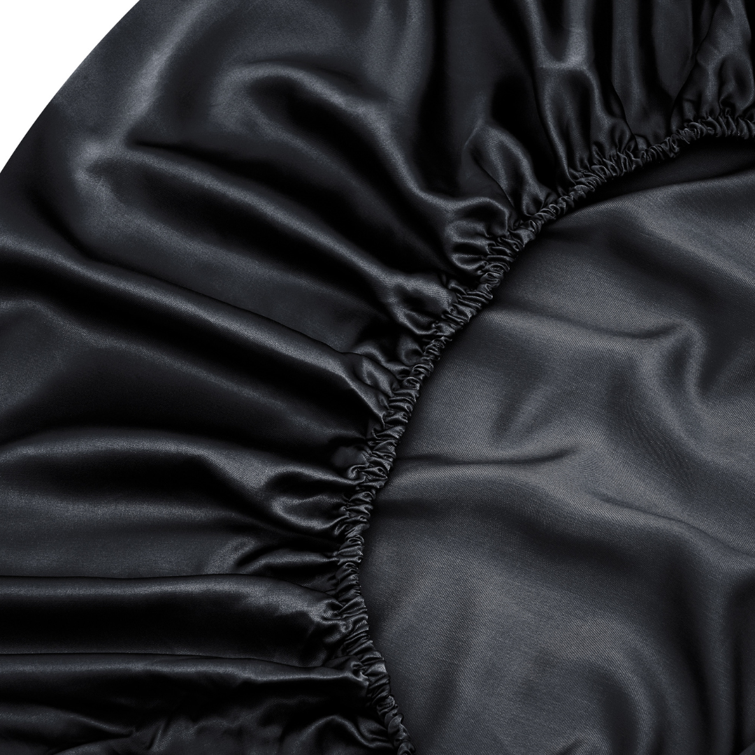 Close-up of the Black Fitted Sheet Set, featuring smooth, shiny fabric and gathered elastic edges that highlight the silky texture and softness.