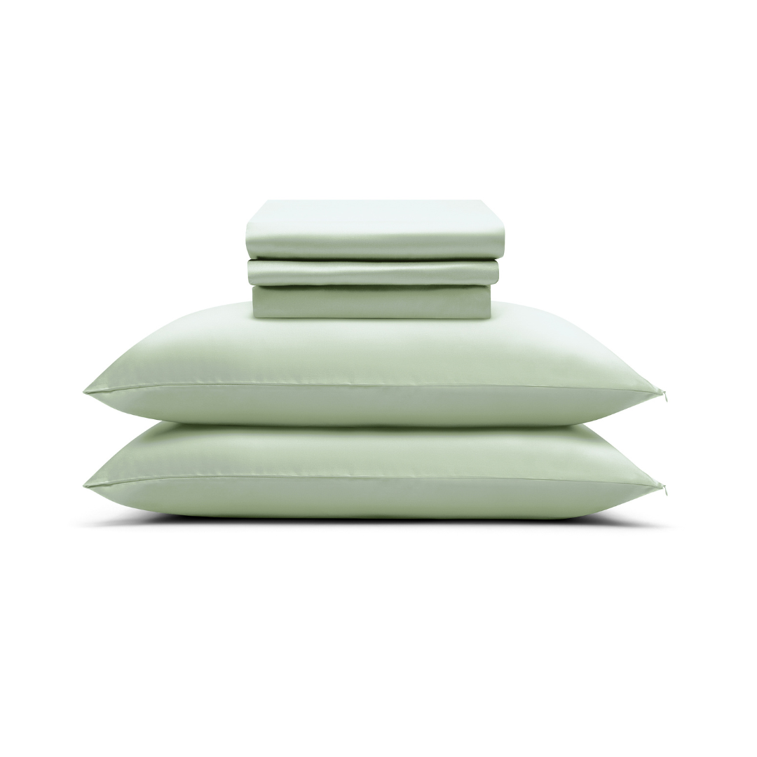 A neatly folded Complete Sheet Set (4-Piece) in light green, featuring two stacked pillowcases and silky soft fitted and flat sheets, arranged against a white background.