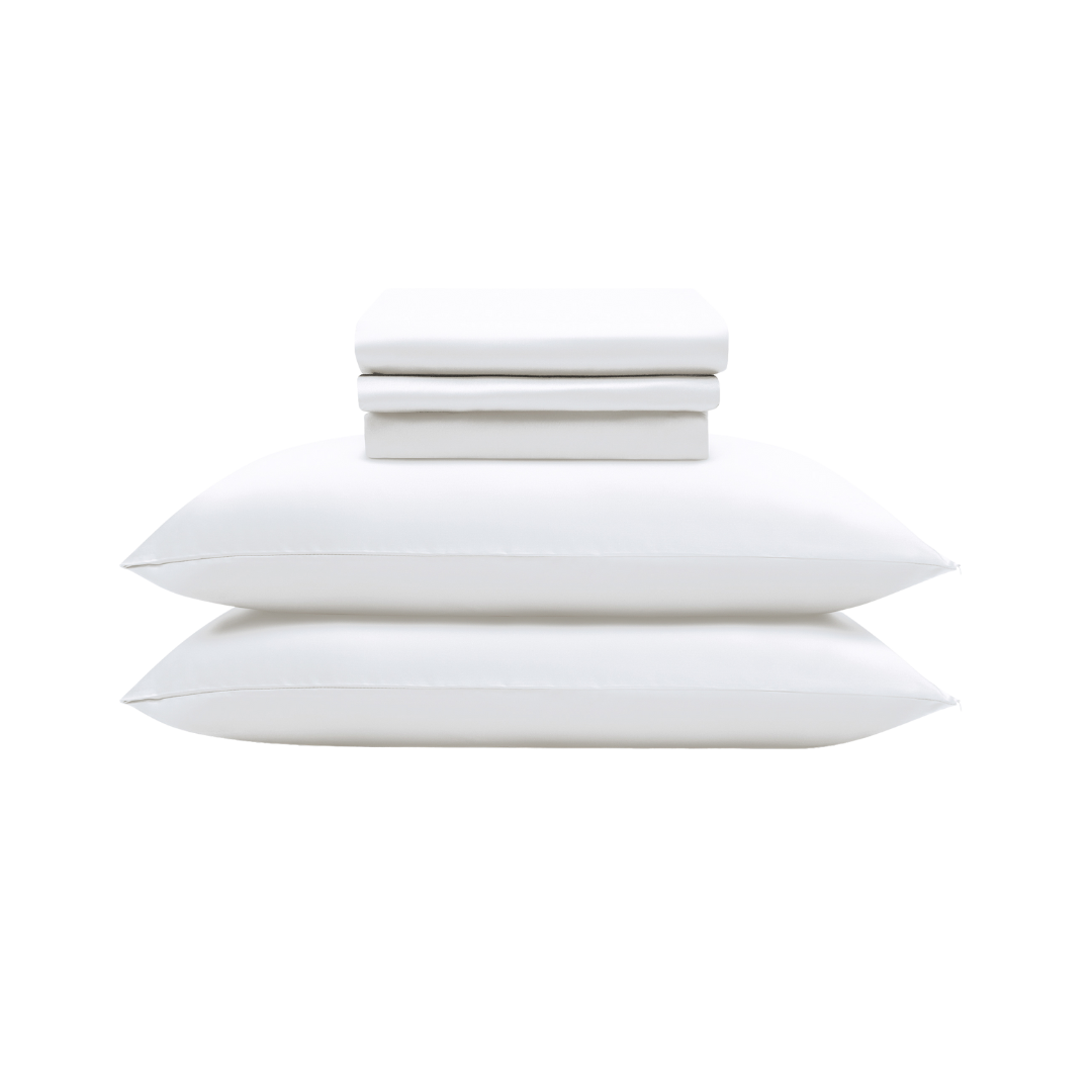 The Complete Sheet Set (4-Piece) features silky soft, neatly stacked sheets and two pillows, including two folded white sheets, displayed on a light background.