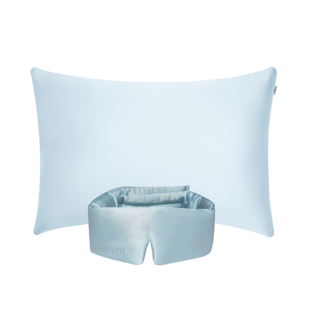 The Deep Sleep Bundle, featuring a light blue pillow with a cooling pillowcase and a matching silky blackout sleep mask, is displayed upright against a white background.