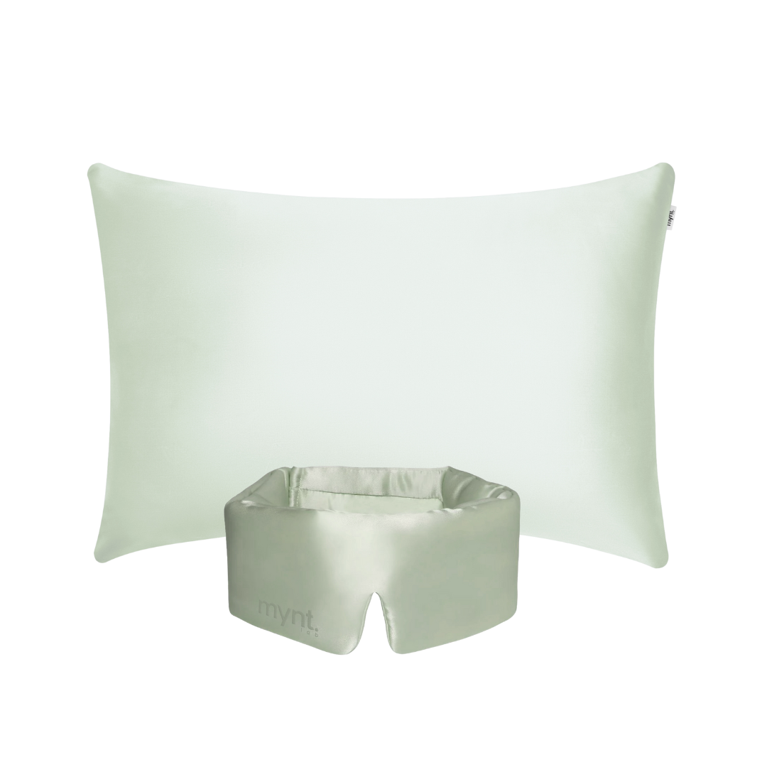 The Deep Sleep Bundle features a light green rectangular pillow with a cooling pillowcase placed behind a matching light green silky blackout sleep mask, which has an opening at the bottom and "mynt lab." printed on it, set against a white background.