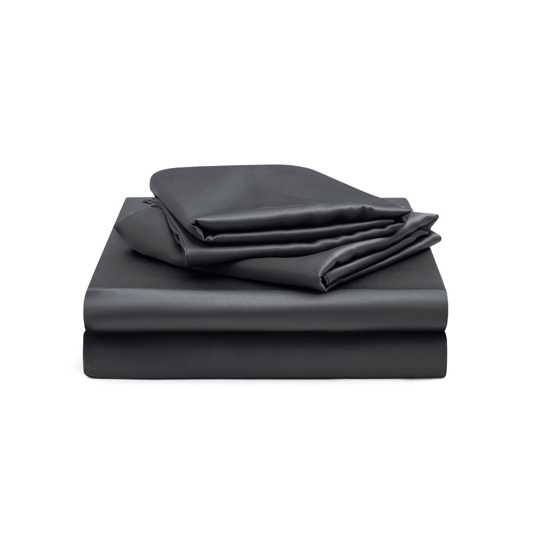 The Fitted Sheet Set (3-Piece) in dark gray features silky soft, neatly folded sheets—fitted sheet, flat sheet, and pillowcases—stacked on a white background.