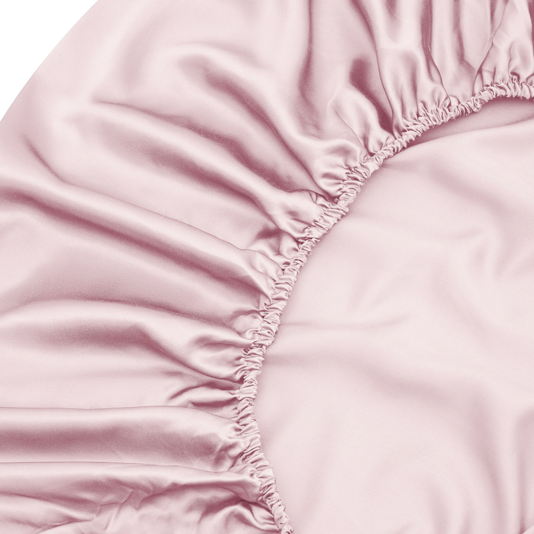 Close-up of the Fitted Sheet Set (3-Piece) in light pink satin, featuring gathered elasticized edges and a smooth, shiny texture—ideal for anyone looking for silky soft sheets.