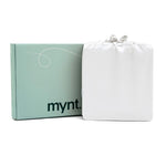A mint green Mynt Lab box labeled "mynt" sits beside a white drawstring bag against a plain white background—ideal for storing the MyntFusion™ Complete Sheet Set (4-Piece).