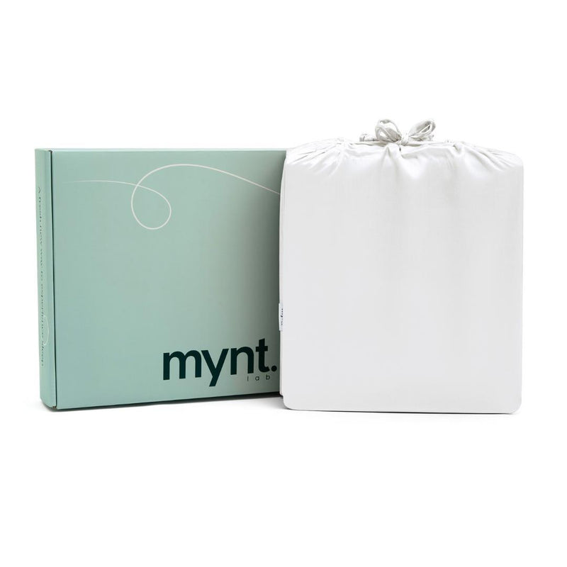 A mint green Mynt Lab box labeled "mynt" sits beside a white drawstring bag against a plain white background—ideal for storing the MyntFusion™ Complete Sheet Set (4-Piece).