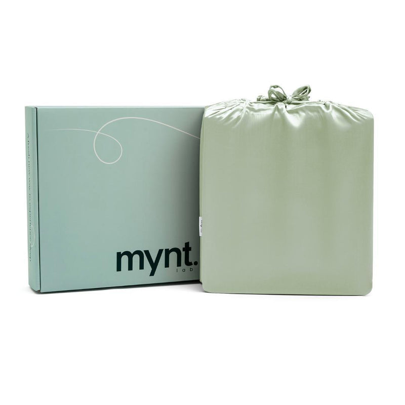 A light green Mynt Lab box stands next to a matching drawstring bag, both sleek and minimalist—ideal for gifting the MyntFusion™ Complete Sheet Set (4-Piece) to elevate any bedroom.