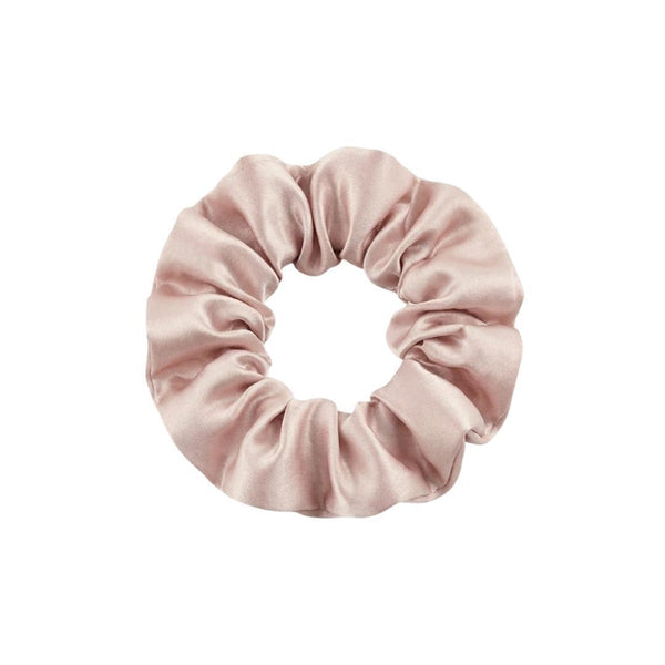 A light pink, satin scrunchie is shown against a plain white background. The scrunchie has a soft, shiny texture and is gathered in a circular shape.