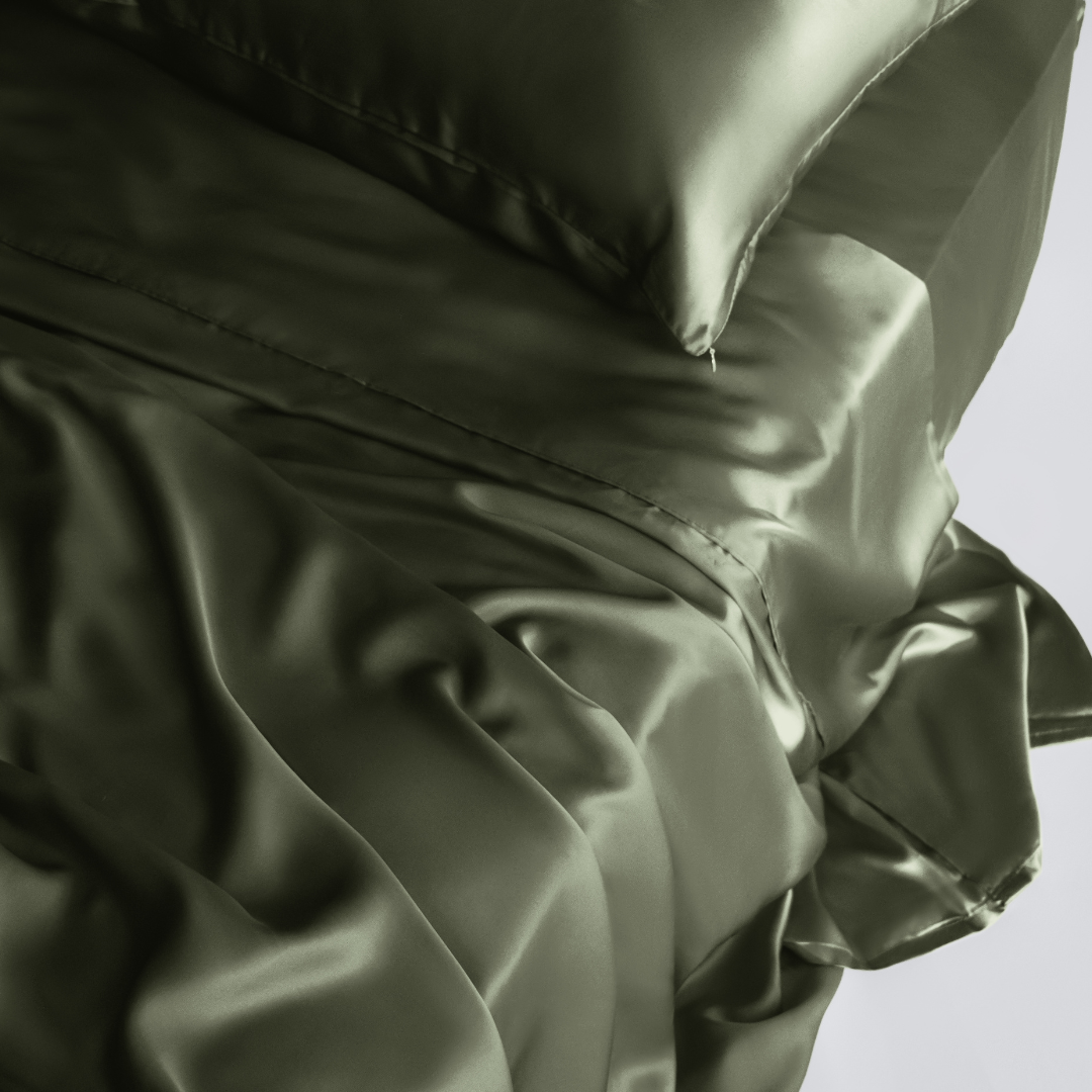 The Complete Sheet Set (4-Piece) features smooth, shiny, olive green silky soft sheets and pillowcases that are softly draped and wrinkled for a luxurious, elegant look.