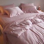 Bed with pink bedding and pillows in a softly lit room.