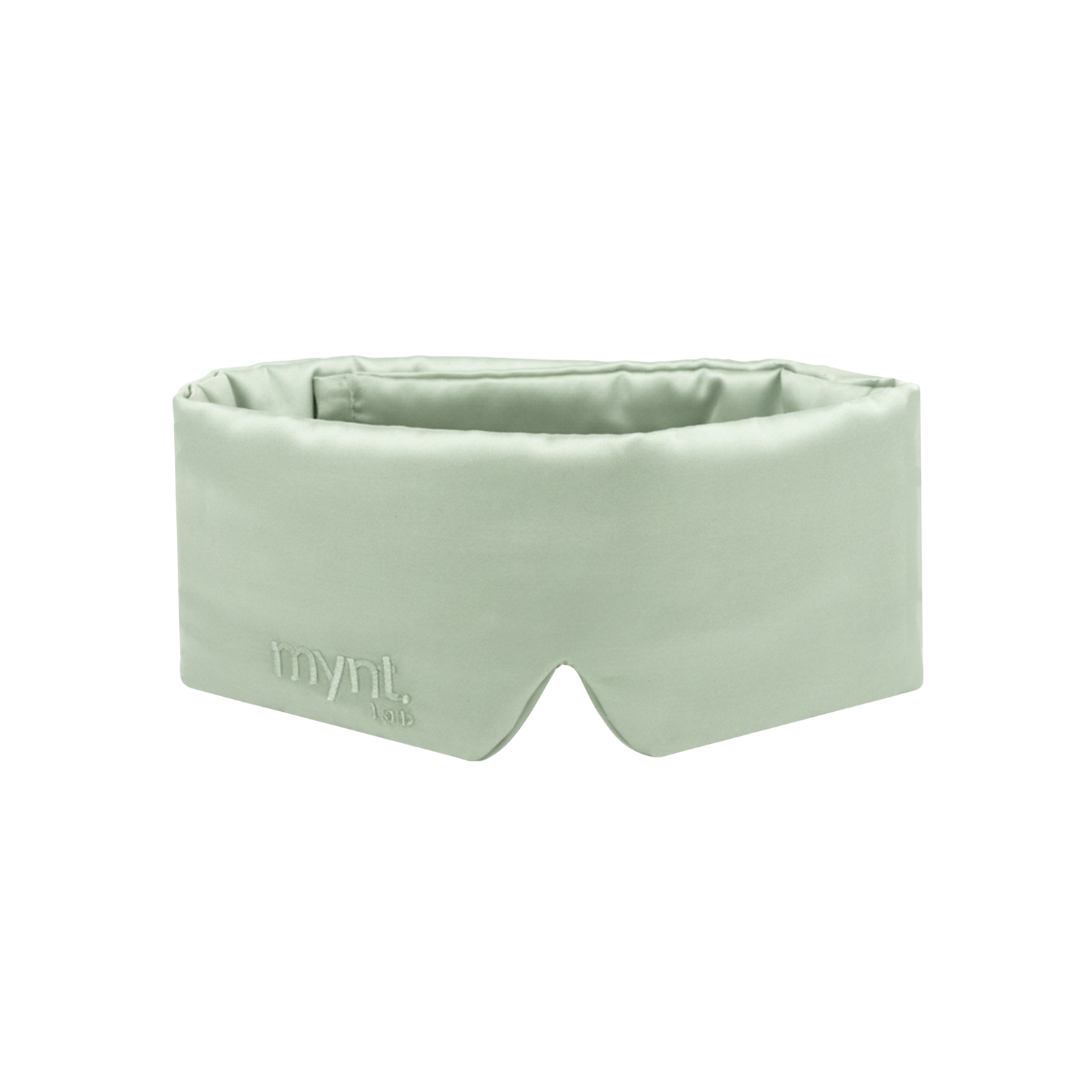 A sage green, padded sleep mask with a notch for the nose and mynt lab embroidered on the front. The mask has a wide, wraparound design.
