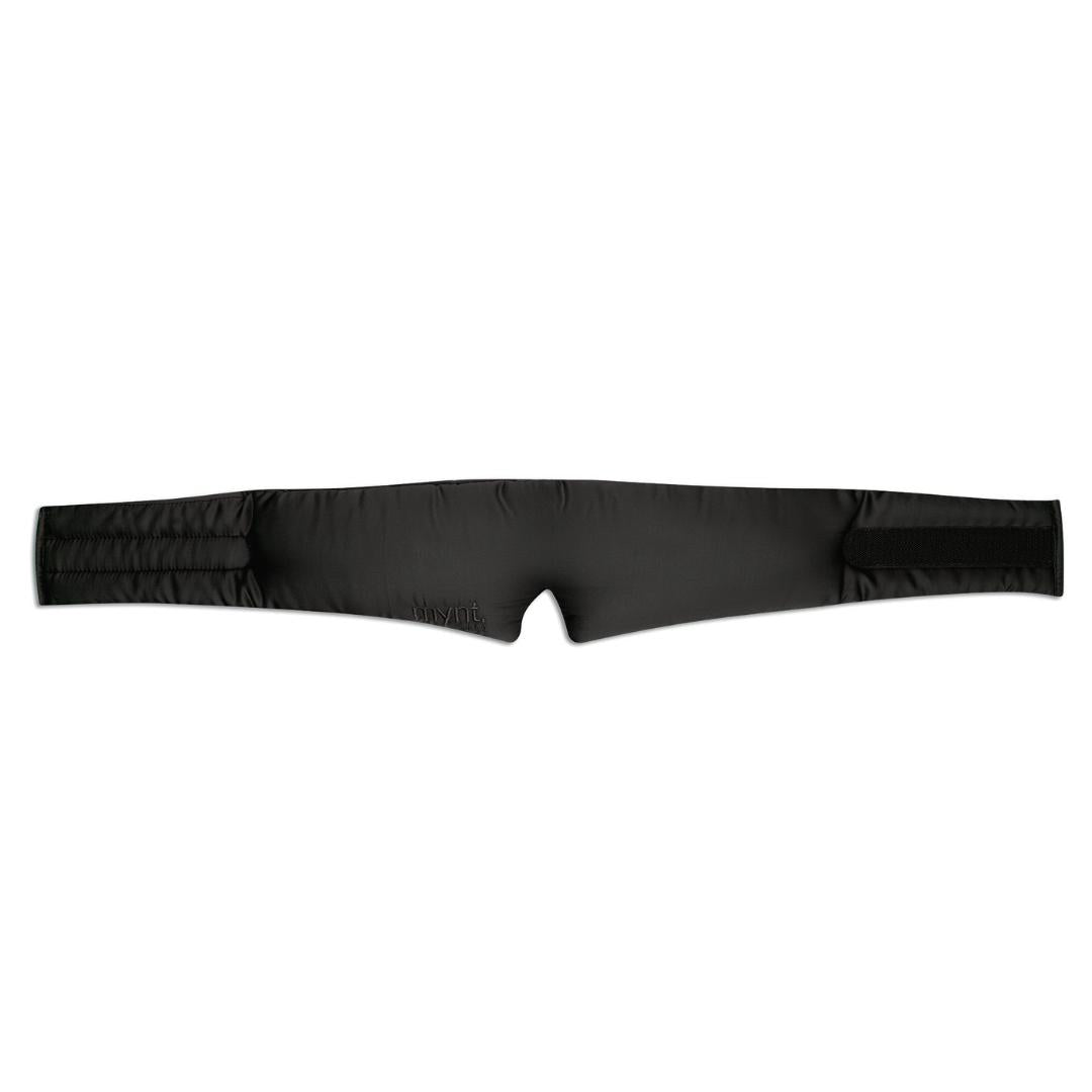 The Sleep Mask is a black, padded, adjustable strap with Velcro ends and a small central cutout for light blocking, featuring subtle stitched detailing. Laid flat on a white background, it's designed to promote deep sleep.