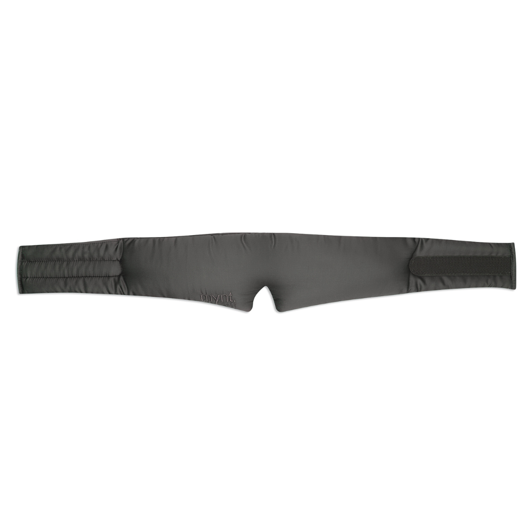 The Sleep Mask features a charcoal, padded, and slightly quilted strap with Velcro fasteners on both ends. Designed to block light for deep sleep, it has subtle stitching and a small embroidered logo for a soft, comfortable fit.