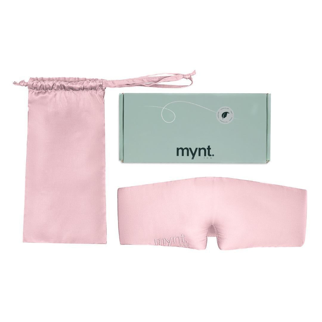 The Sleep Mask includes a pink silky mask with mynt lab embroidery, a matching drawstring pouch, and a mint green mynt lab branded box - perfect for blocking light and encouraging deep sleep- all displayed on a white background.
