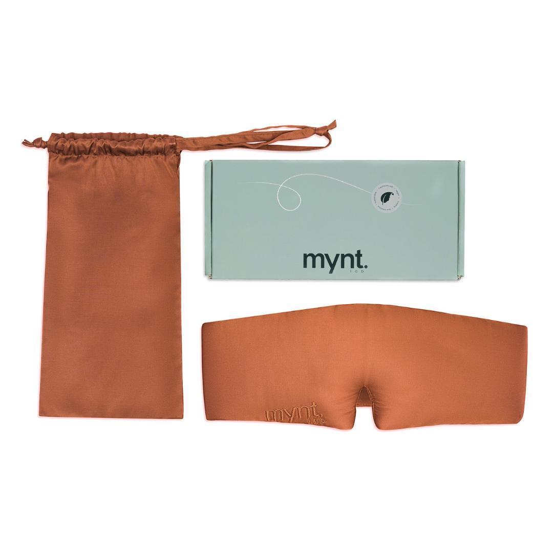 The Sleep Mask in terracotta, paired with a matching drawstring pouch and a mint green mynt lab logo box, is displayed flat on a white background.