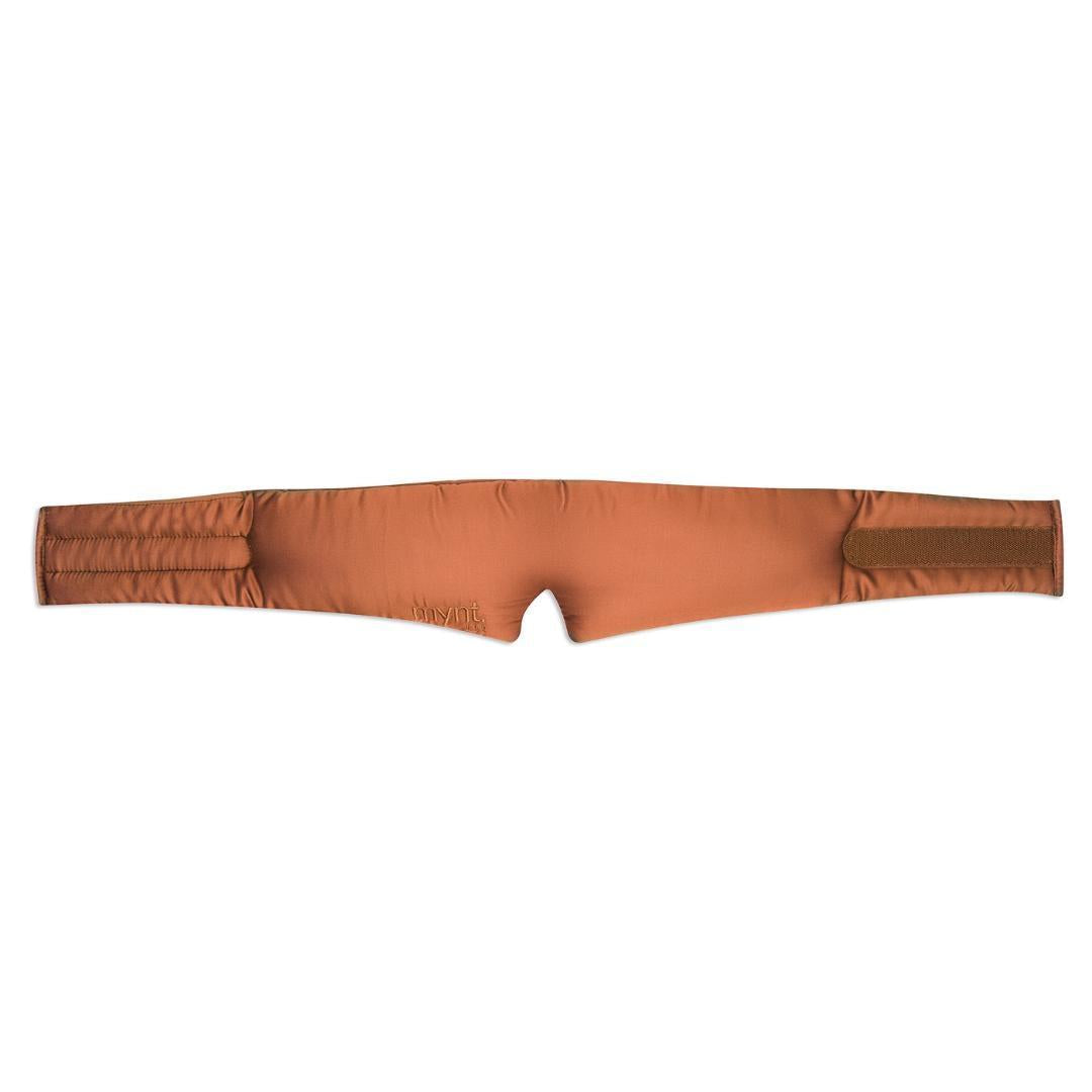 The Sleep Mask is a terracotta, padded fabric mask with a contoured centre notch to block light and velcro fasteners on both ends, shown laid flat on a white background - ideal for deep sleep.