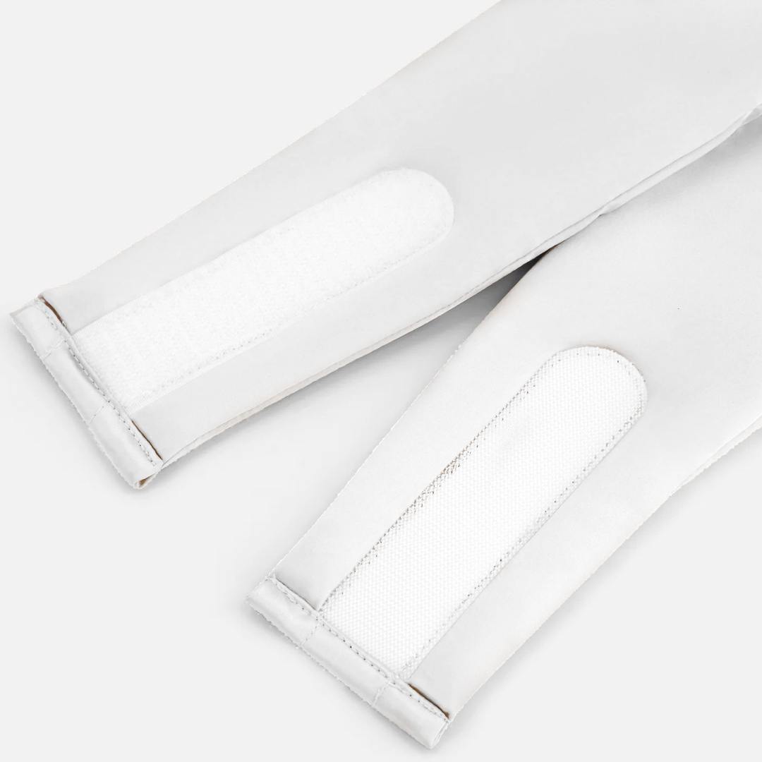 Close-up of two white Velcro straps attached to the cuffs of a Sleep Mask on a light surface, highlighting stitched and textured fasteners designed to effectively block light and promote deep sleep.