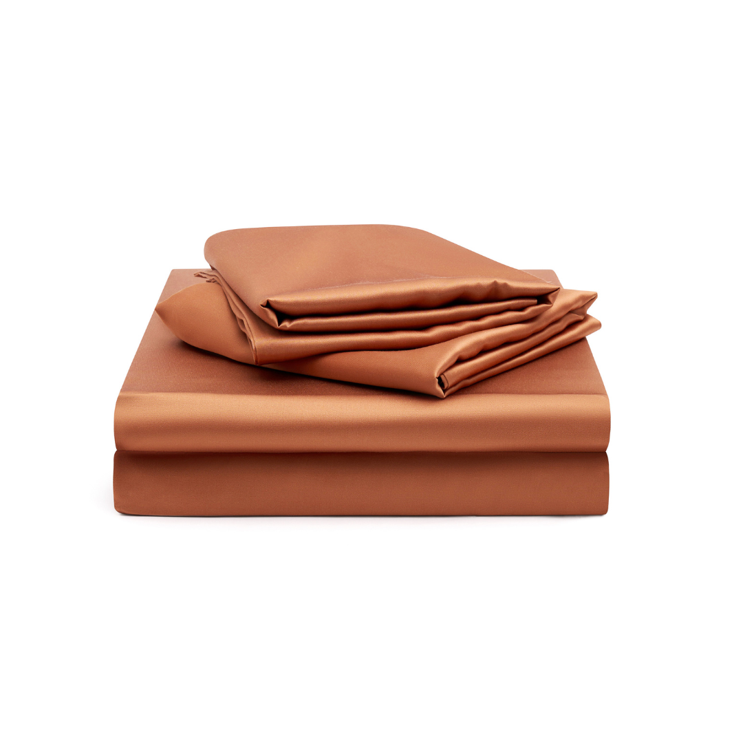 A neatly folded Fitted Sheet Set in a silky soft terracotta colour displayed on a white background.