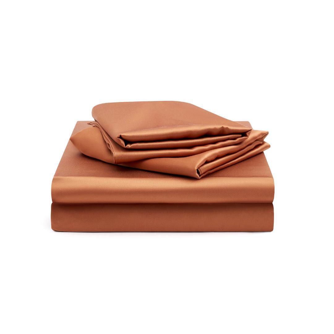 A neatly folded Fitted Sheet Set in a silky soft terracotta colour displayed on a white background.